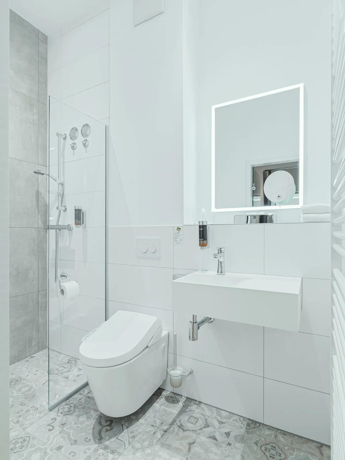 Badezimmer im Familienzimmer mit Dusche und beleuchtetem Spiegel